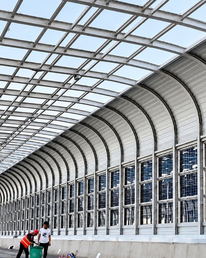 Full-enclosure noise barrier over a dual carriageway, with a metal base course, glazed upper course and curved roof