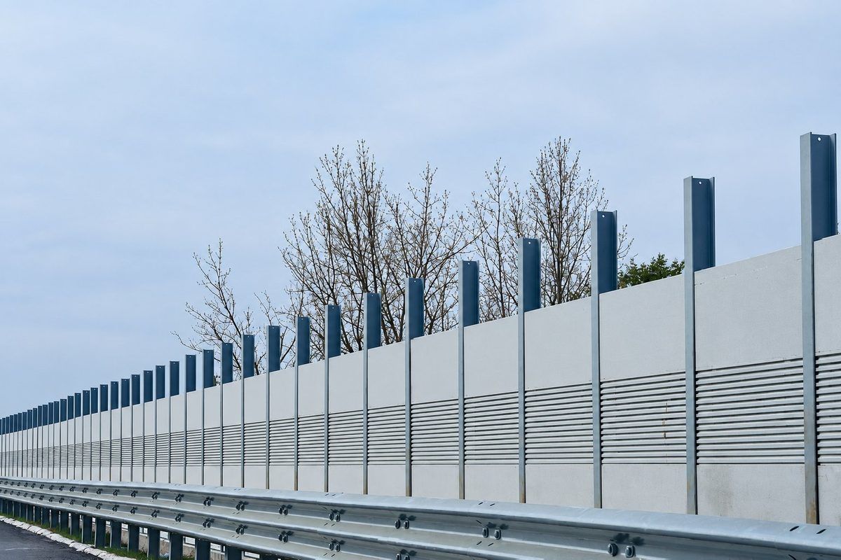 Absorptive metal noise barrier wall with galvanised H-beam posts along a highway