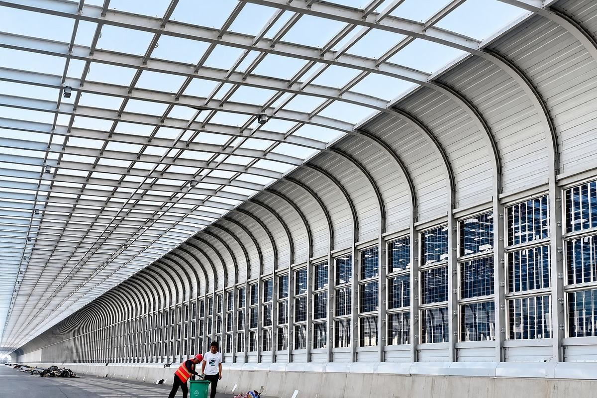 Full-enclosure noise barrier over a dual carriageway, metal base course and glazed upper course under a curved roof